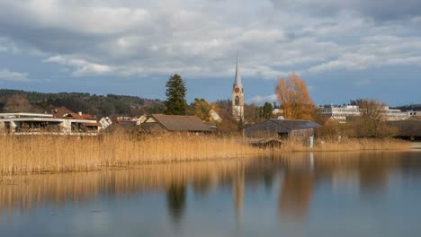 nubes se mueven sobre una iglesia cerca de un lago en suiza