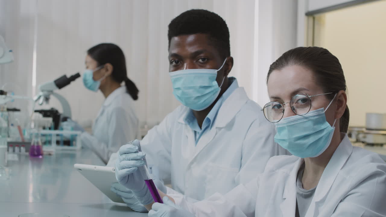 Ralenti de scientifiques examinant une solution dans une éprouvette et posant