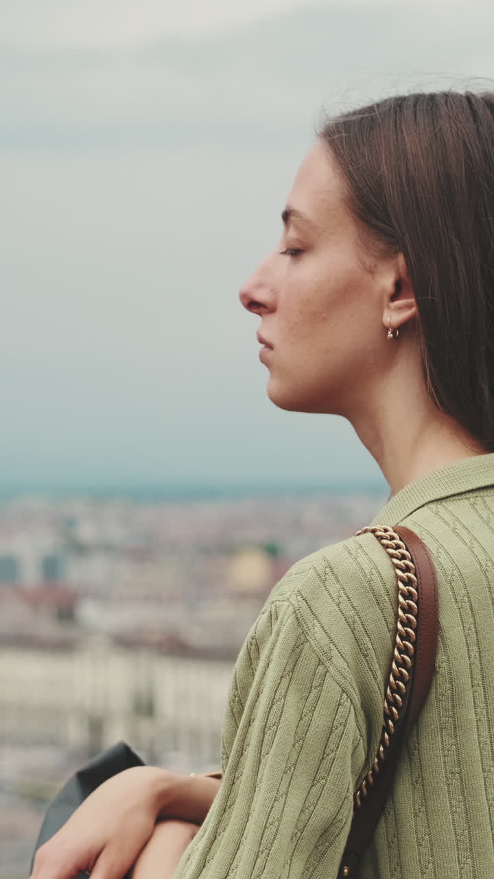 Giovane donna pensierosa che guarda lo skyline della città