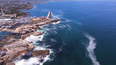 drone tilt-up revela disparo sobre la costa de hermanus y el nuevo puerto, sobrecargada