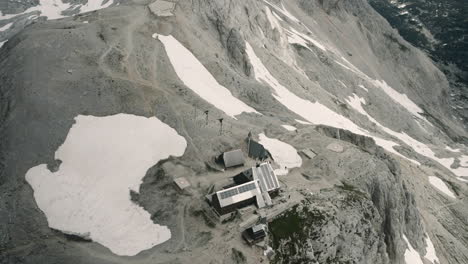 Shot-of-slovenian-mountains-out-of-helicopter-of-a-mountain-cottage-in-Slovenian-Julijan-Alps,-surrounded-with-some-snow