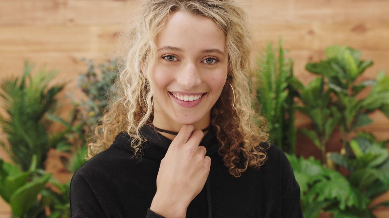 Young Woman With Curly Blonde Hair Smiling at Camera