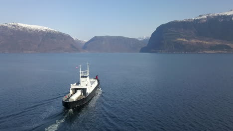 a ferry traveling across a fjord in norway, drone tracking shot