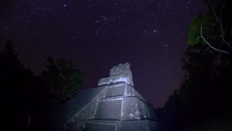 el lapso de la noche captura la majestuosa belleza de un cielo lleno de estrellas sobre una antigua estructura de piedra, rodeada de siluetas de árboles