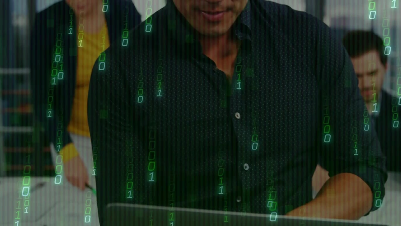 Presenter typing laptop at table, showing green binary code while team reviewing security data
