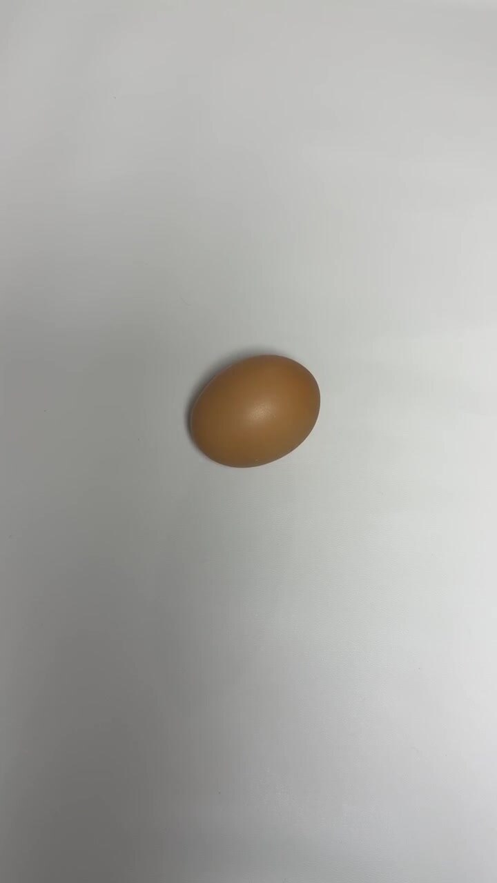 Hand Placing and Removing a Single Brown Egg on White Surface