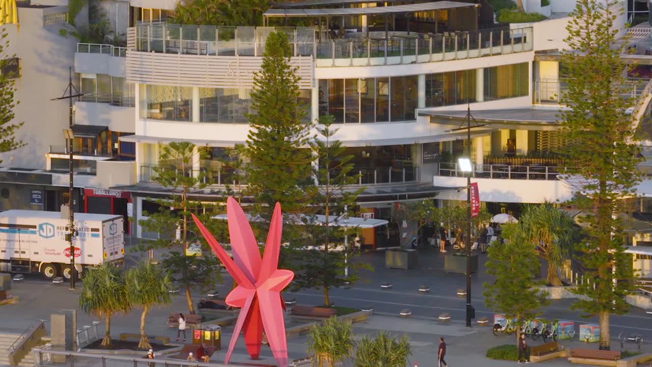 Vídeo de dron con edificios urbanos contemporáneos, pinos y una gran escultura de una estrella rosa