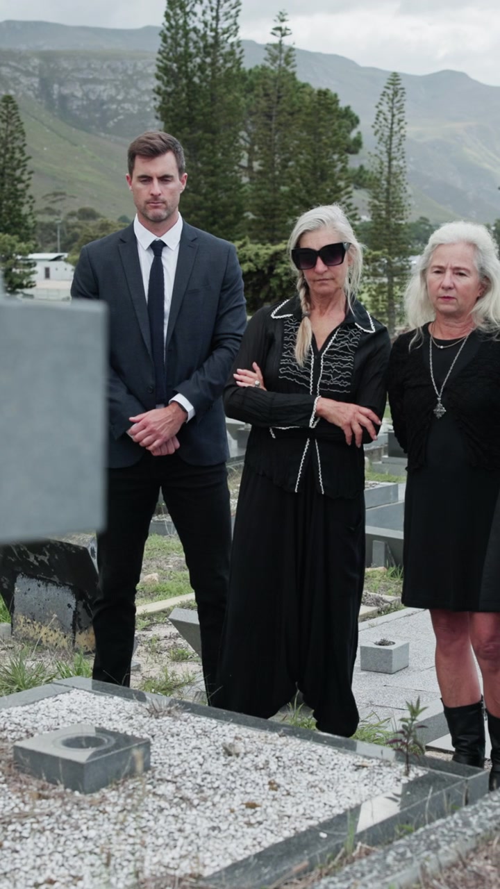 Group of People in Mourning Attire Standing at a Cemetery