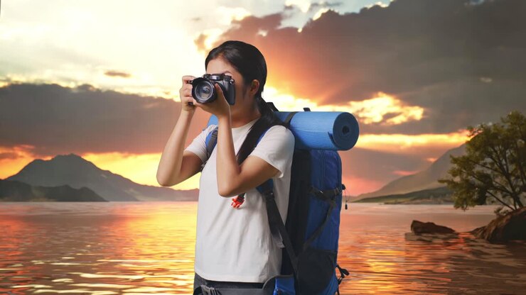 Side View Of Asian Female Hiker With Mountaineering Backpack Using A Camera Taking Picture At A Lake