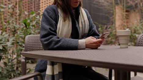 woman using phone in an outdoor cafe