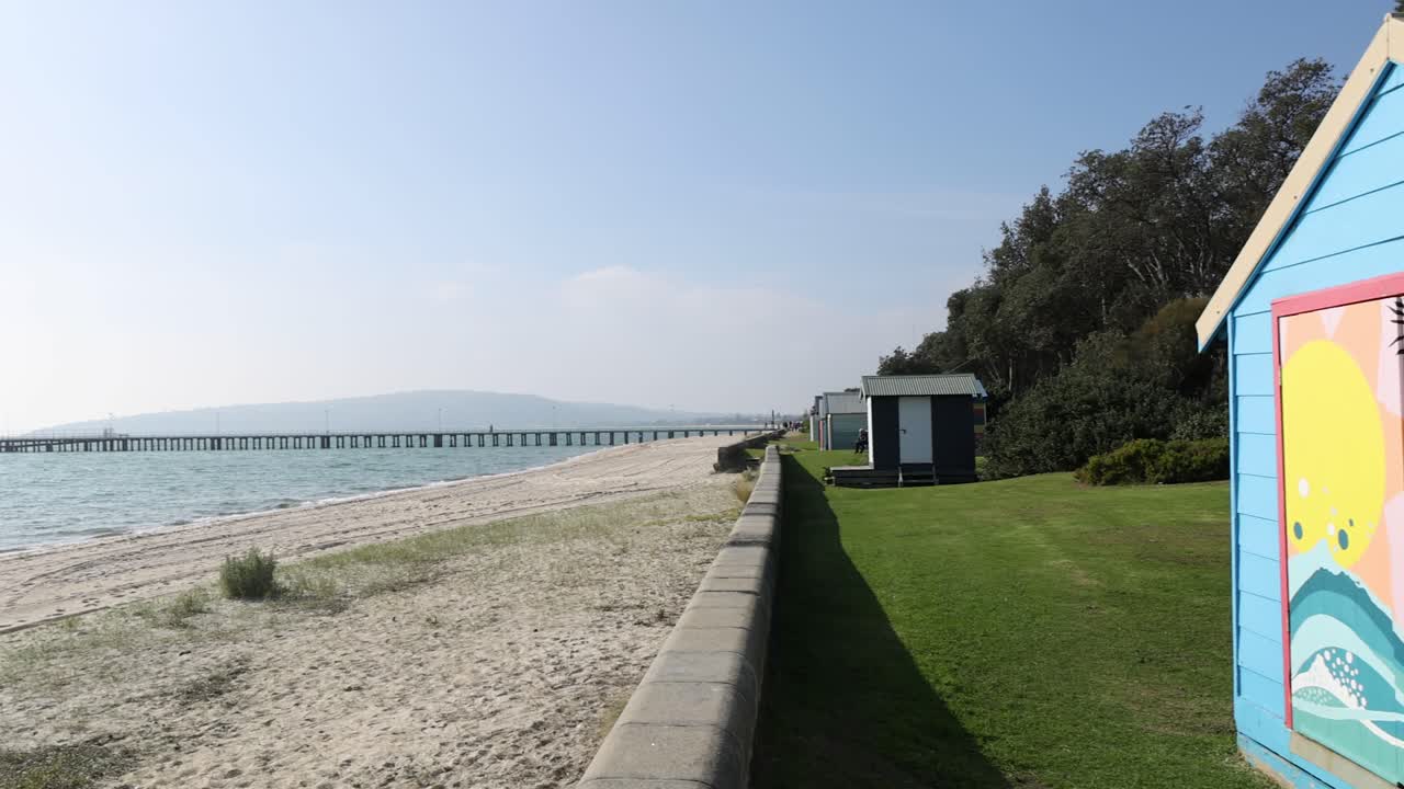 Colorful beach boxes near a scenic pier