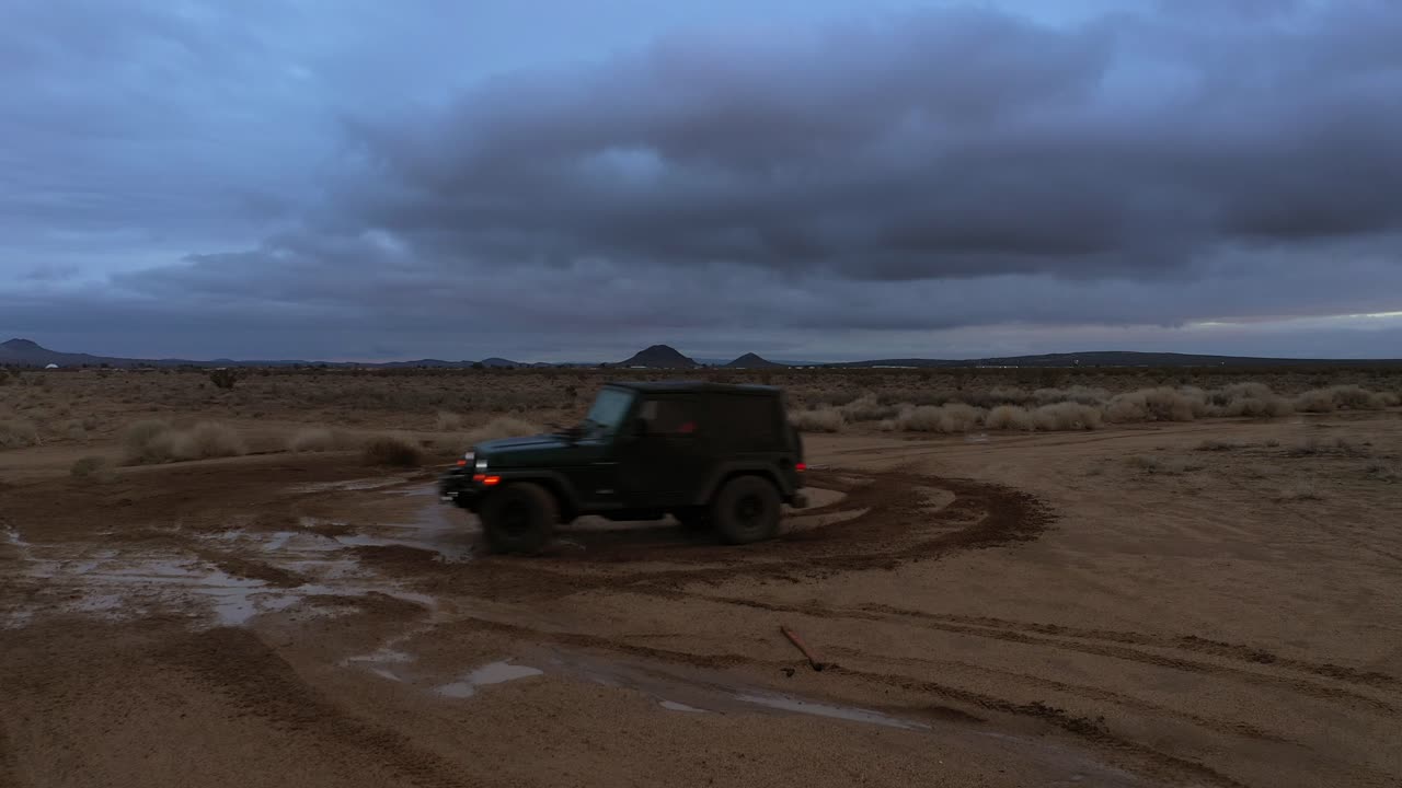 클라우드 버스트 후 모하비 사막의 진흙에서 지프와 함께 도넛 회전 - 공중 보기