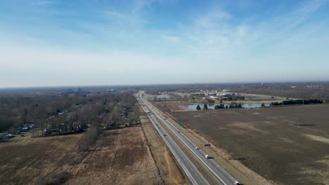 Drone-flying-in-middle-of-winter-in-Ohio-overhead-a-2-lane-highway-with-a-small-lake-in-frame