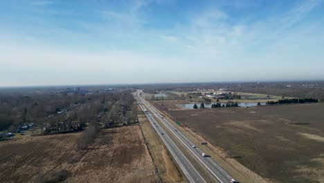 drone flying in middle of winter in ohio overhead a 2 lane highway with a small lake in frame