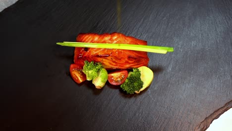 artistic plating of grilled salmon filet with vegetables on black slate