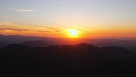 rack focus of setting sun casting orange red golden hour light and mountains to a blur