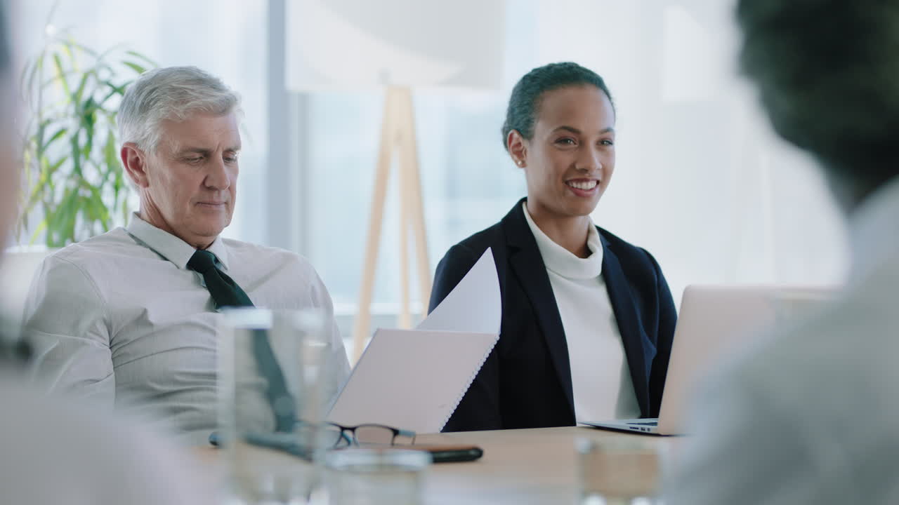 beautiful mixed race business woman in boardroom meeting smiling enjoying casual conversation with colleagues sitting at table working on project in office 4k