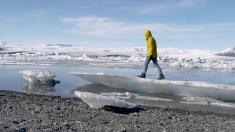 Junger-Blonder-Männlicher-Reisender,-Der-Auf-Eiskanal-In-Der-Gletscherlagune-In-Island-Geht