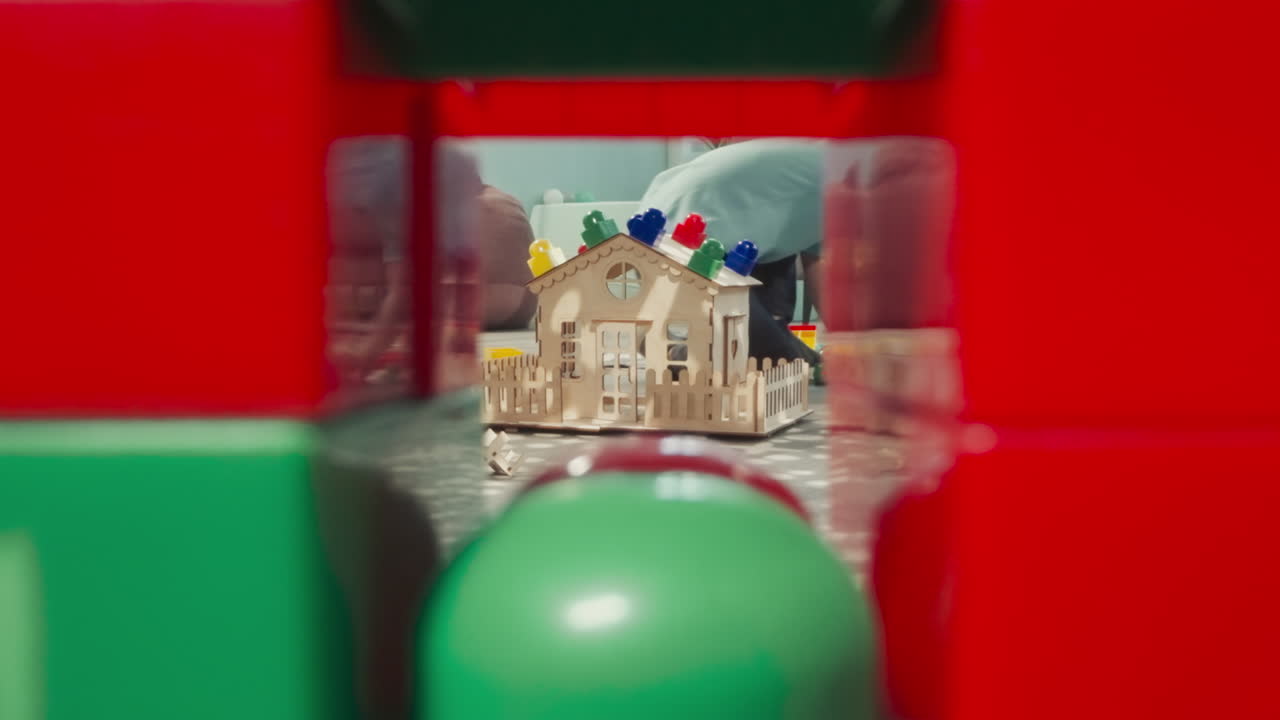 소년은 여자 아기 인형을 흔들면서 플라스틱 블록으로 놀고 있습니다.