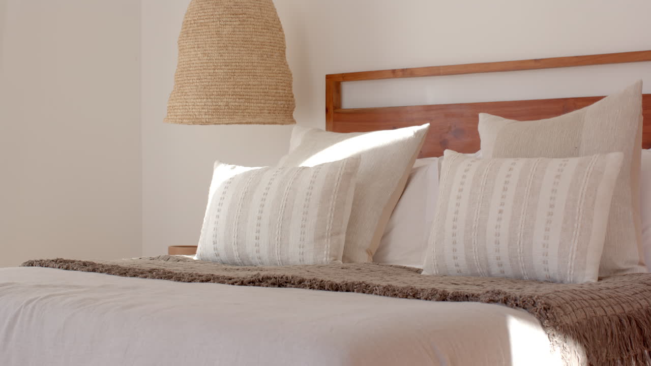 Cozy bedroom with decorative pillows and woven lamp creating serene atmosphere, at home