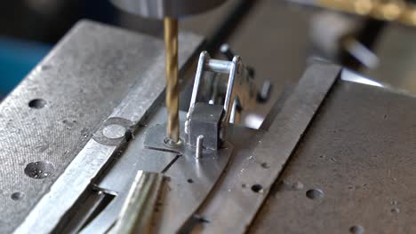 titanium coated drill making precise hole in steel plate for the creation of kitchen cutting utensils, close up shot