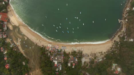 Overhead-View-Of-Yelapa-Beach-Town-And-Boats-Sailing-And-Floating-In-The-Bahia-de-Banderas,-Jalisco,-Mexico