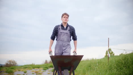 agricultor serio con carretilla en la granja
