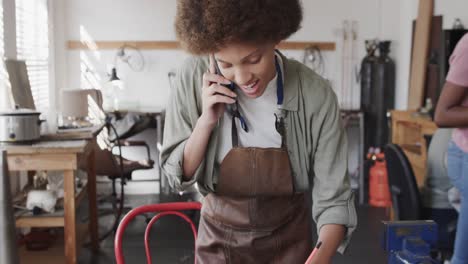 Vielbeschäftigte-Biraziale-Arbeiterin,-Die-Im-Schmuckstudio-In-Zeitlupe-Auf-Dem-Smartphone-Spricht