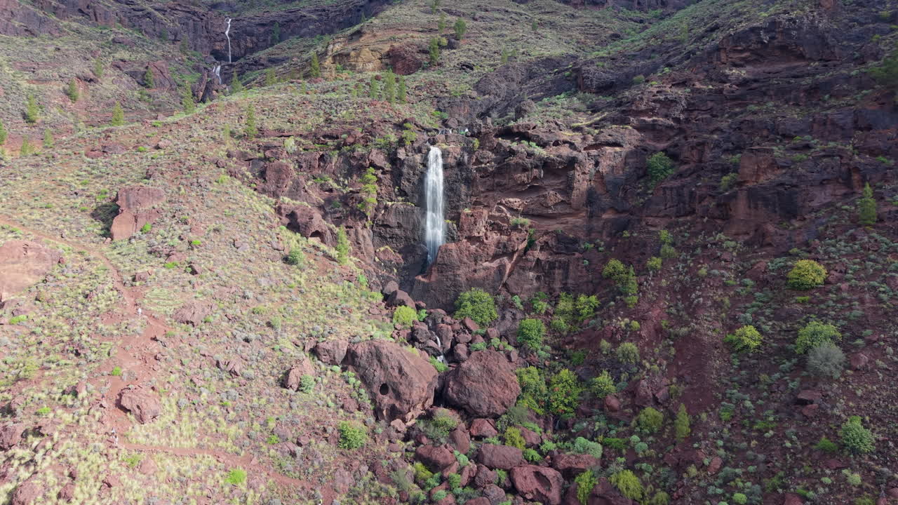 Aerial drone flying towards a waterfall in Azulejos de Veneguera, Gran Canaria