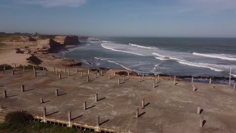 Aerial-orbiting-around-person-walking-on-seafront-abandoned-building