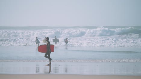 body boarder walking on the beach with his orange bodyboard in his wetsuit