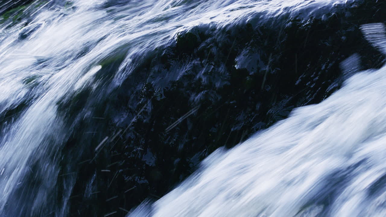Water flowing in rapids, over a rock, close up