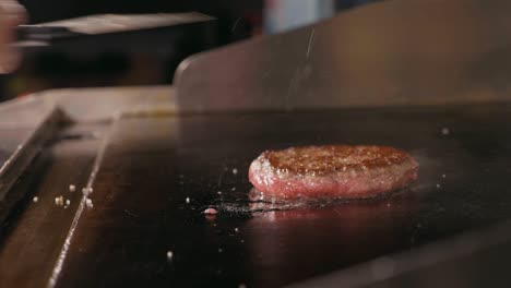 slow motion shot of frying cutlet for burger on electric commercial grill.