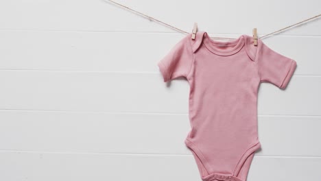 Video-of-pink-baby-grow-hanging-on-clothes-begs-on-line-with-copy-space-on-white-background