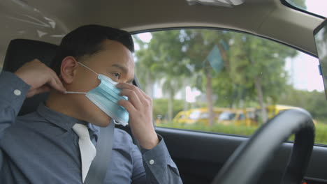 business man wearing a face mask inside his car before driving due to covid-19 pandemic