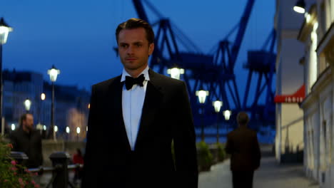 elegant man in a tuxedo at night in a harbor city