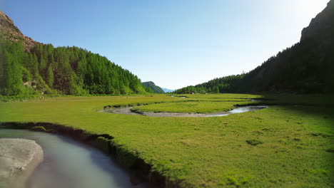 flyover in val masino with river flowing across landscape with mountains in background and sky for copy space