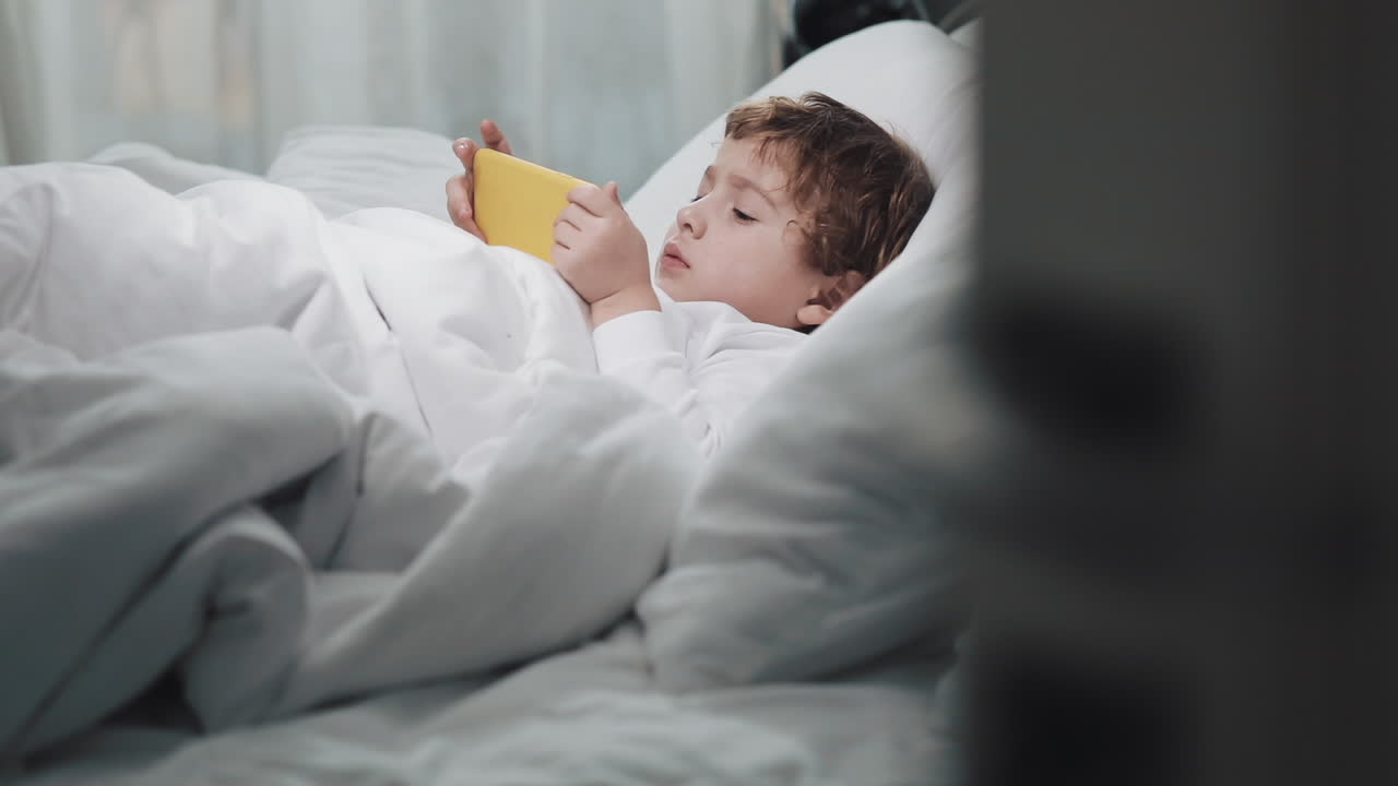 Boy lying in bed using a phone