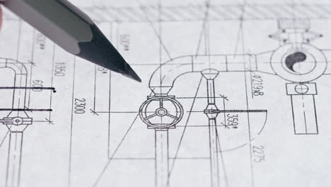 a pencil pointing at a detailed engineering or architectural blueprint