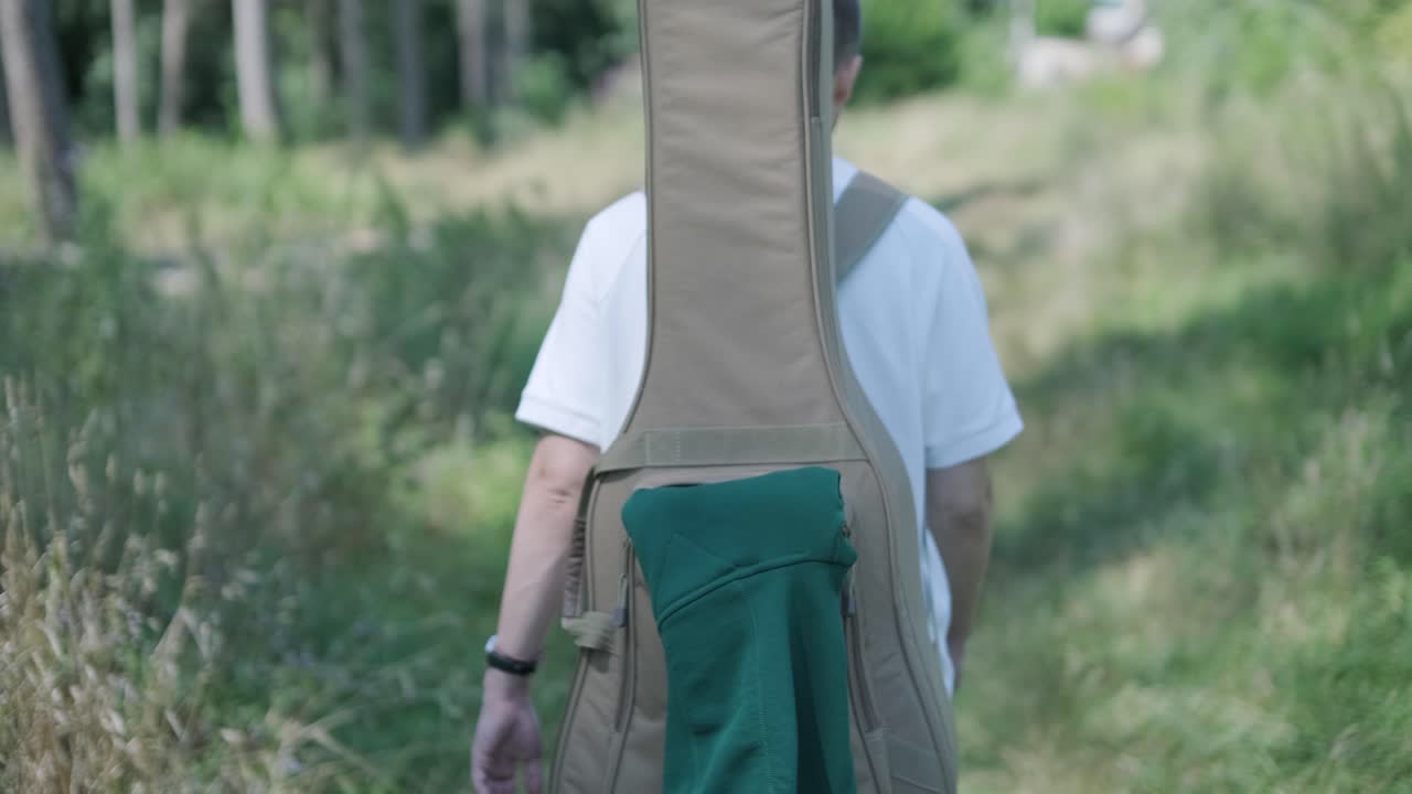 숲 근처의 거리에서 기타를 들고 는 젊은 남자