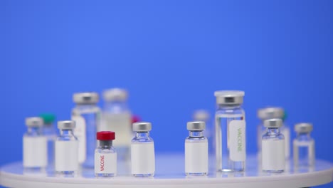 vacuna contra el coronavirus en ampollas de cerca en una mesa de laboratorio fondo azul. medicamentos farmacológicos contra la pandemia de covid-19. vacuna médica de 2019-ncov. pantalla azul, clave de croma. de cerca. lento