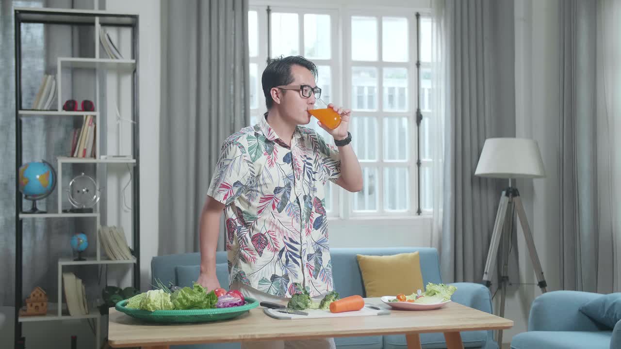 오렌지 주스를 마시고 집에서 채소를 준비하는 남자