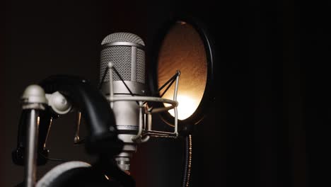 studio recording, professional microphone in the recording studio, microphone near wall with acoustic dampening foam. close-up of microphone on stage against a black background with lighting