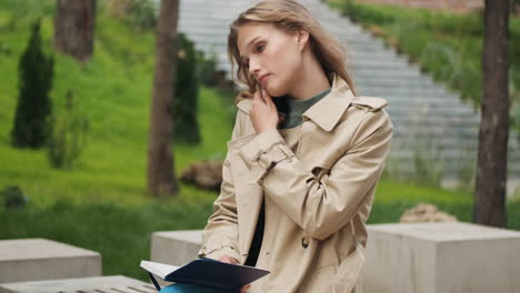 Caucasian-female-student-talking-on-the-phone-with-a-notebook-in-the-park.