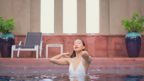 Una-Mujer-Joven-Y-Guapa-En-Una-Piscina-Se-Quita-El-Pelo-Mojado-De-La-Cara