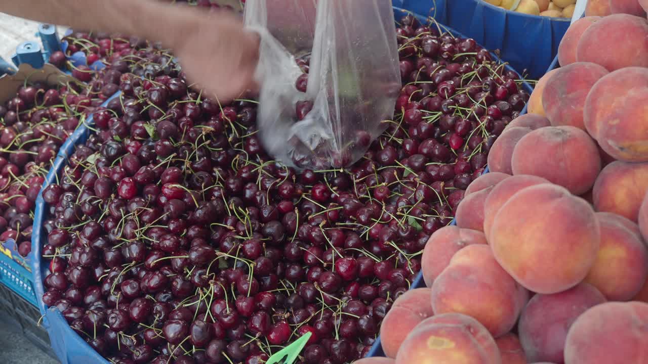 un venditore che vende ciliegie e pesche al mercato