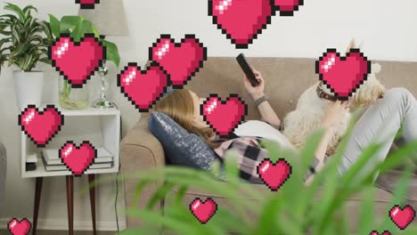 Animation-of-heart-emojis-over-happy-caucasian-woman-using-smartphone-with-dog