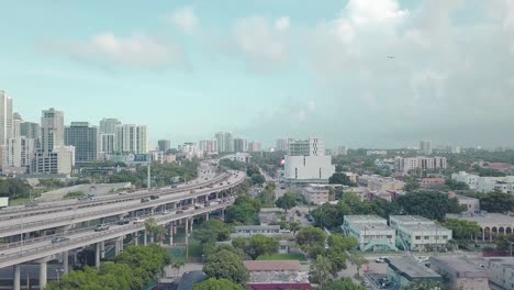 miami traffic with buildings and a plane flying in the background on a sunny day with clouds