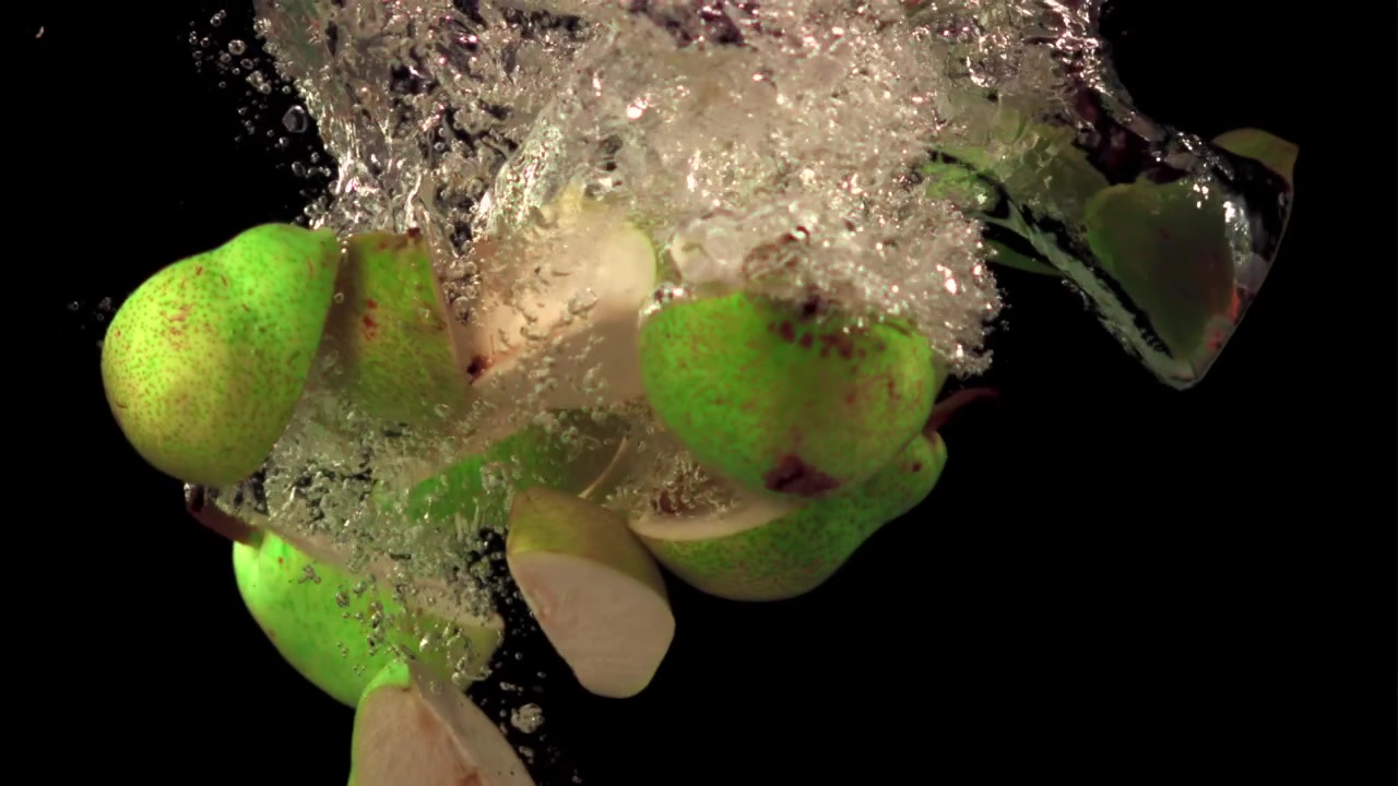 Frische grüne Birnen und Scheiben spritzen ins Wasser
