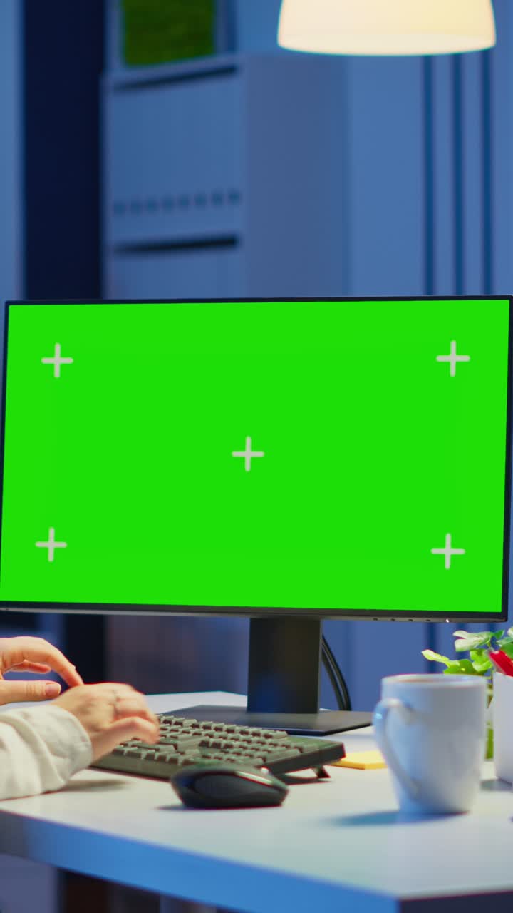 Vertical video: Woman looking at computer with chroma key during night time